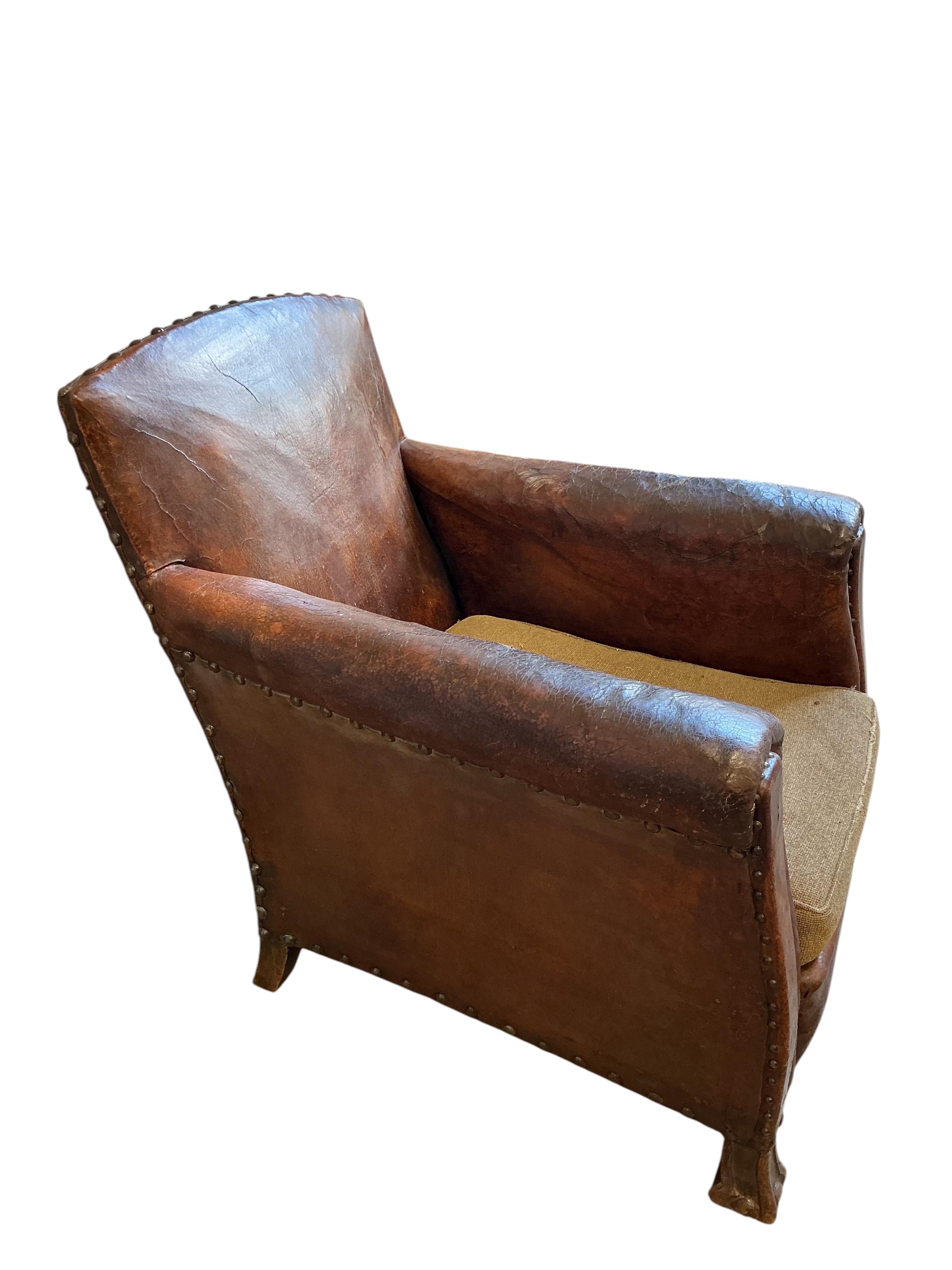 A near pair of early 20th century studded brown leather club chairs, width 79cm, depth 86cm, height 89cm